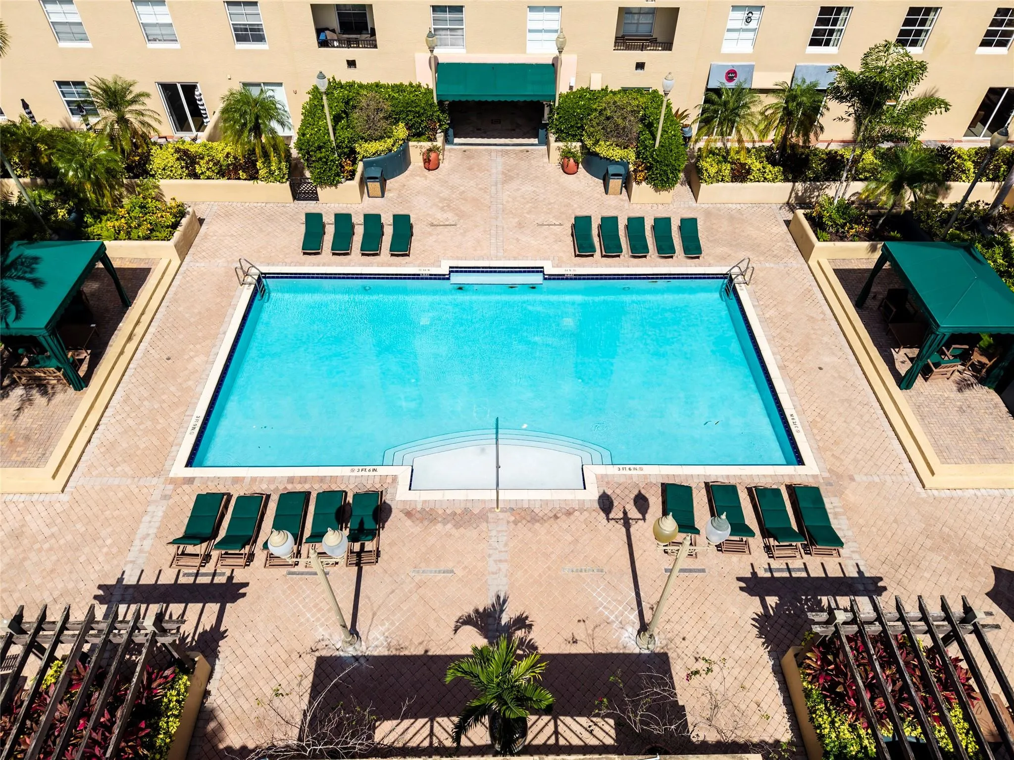 Stunning pool area surrounded by lush landscaping, featuring cabanas, a hot tub, shower, and more for ultimate relaxation.
