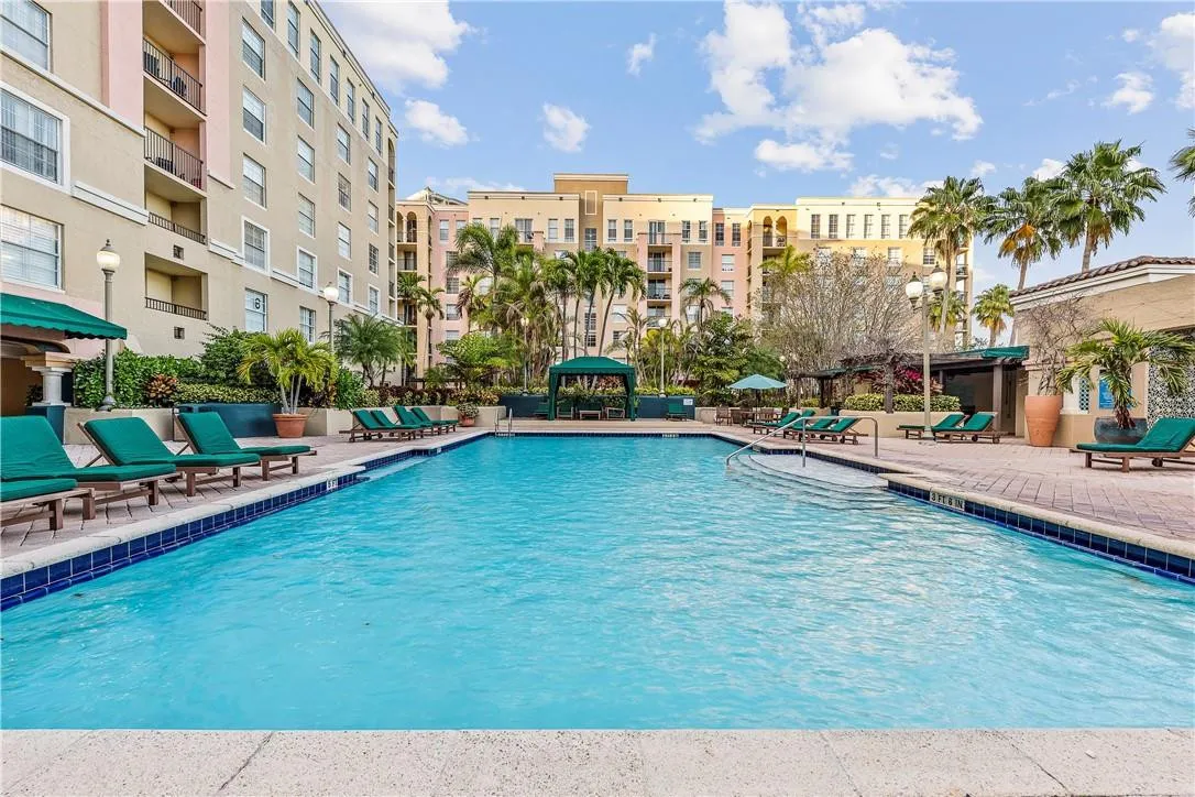 Stunning pool area surrounded by lush landscaping, featuring cabanas, a hot tub, shower, and more for ultimate relaxation.