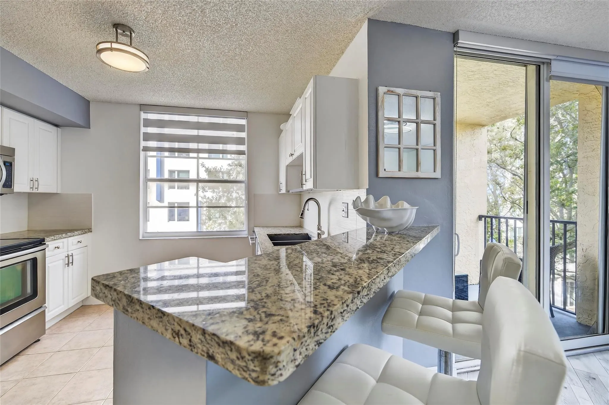 Updated kitchen features stainless steel appliances, granite countertops, and a custom tile backsplash, seamlessly connected to the living space and breakfast bar for easy everyday living and entertaining.
