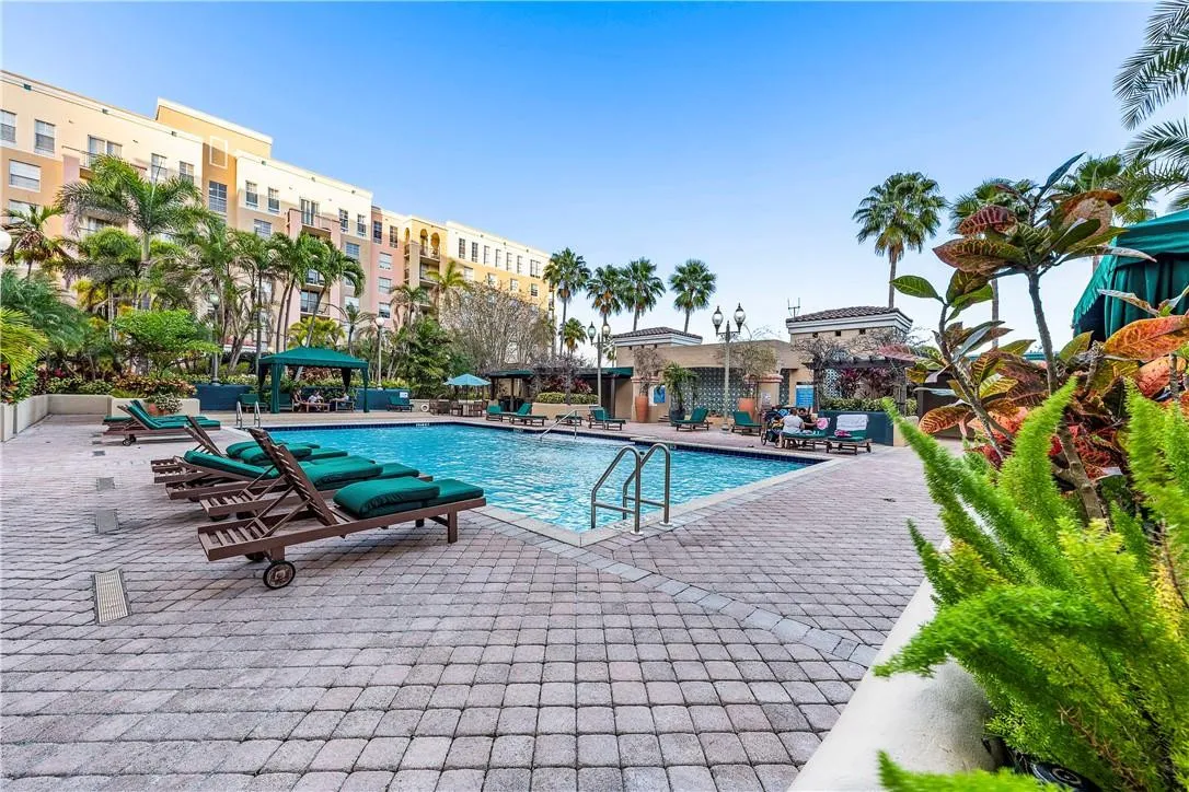 Stunning pool area surrounded by lush landscaping, featuring cabanas, a hot tub, shower, and more for ultimate relaxation.