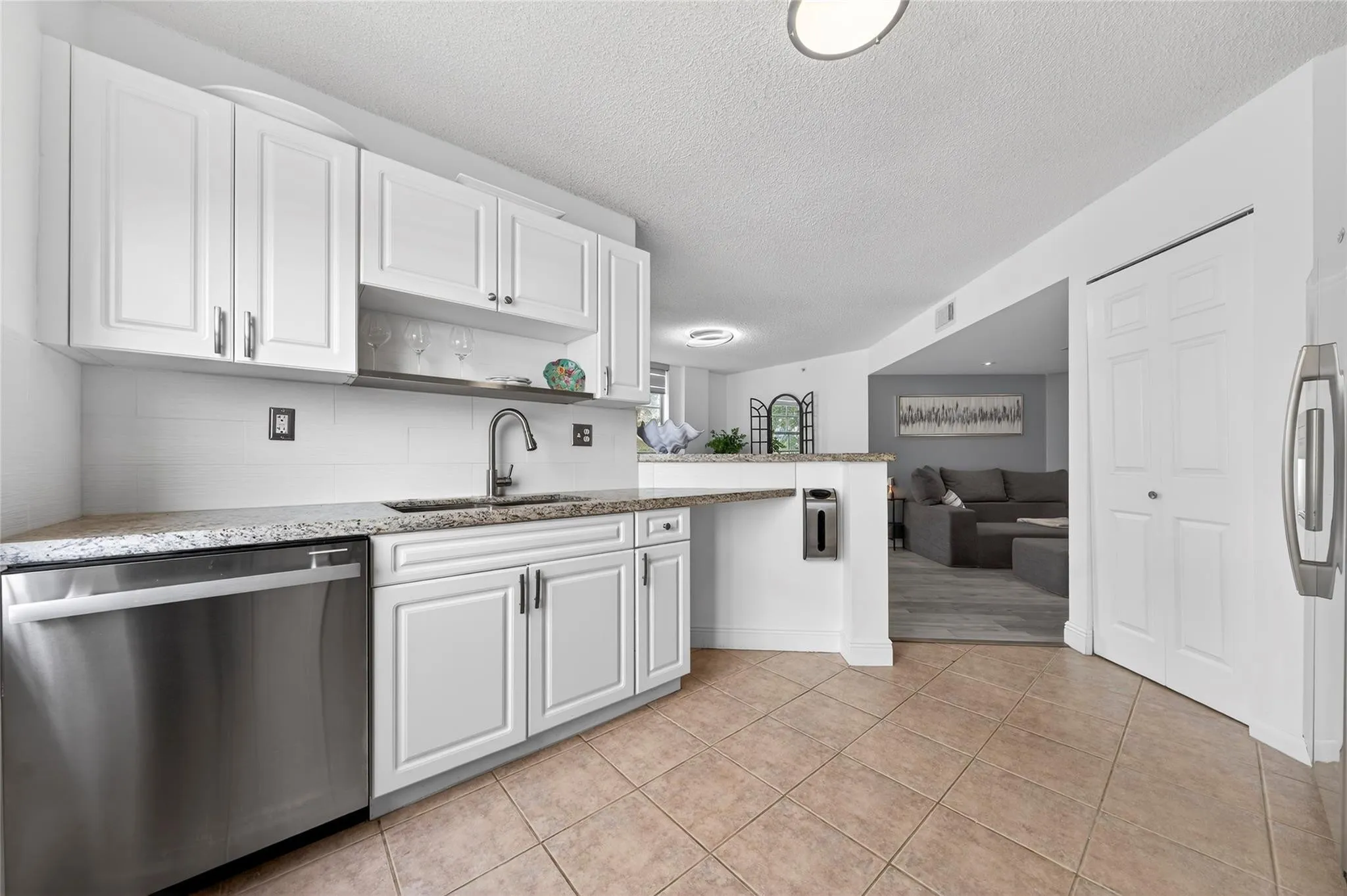 Updated kitchen features stainless steel appliances, granite countertops, and a custom tile backsplash, seamlessly connected to the living space and breakfast bar for easy everyday living and entertaining.