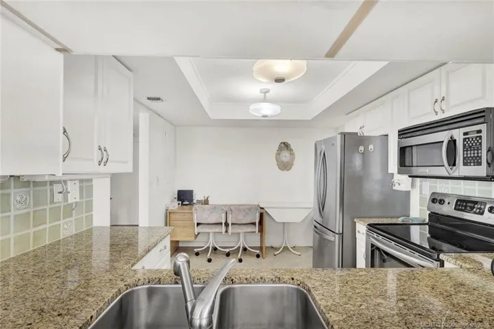 View through the kitchen pass-thru; plenty of room, shaker cabinets, granite counters and tiled backsplash!