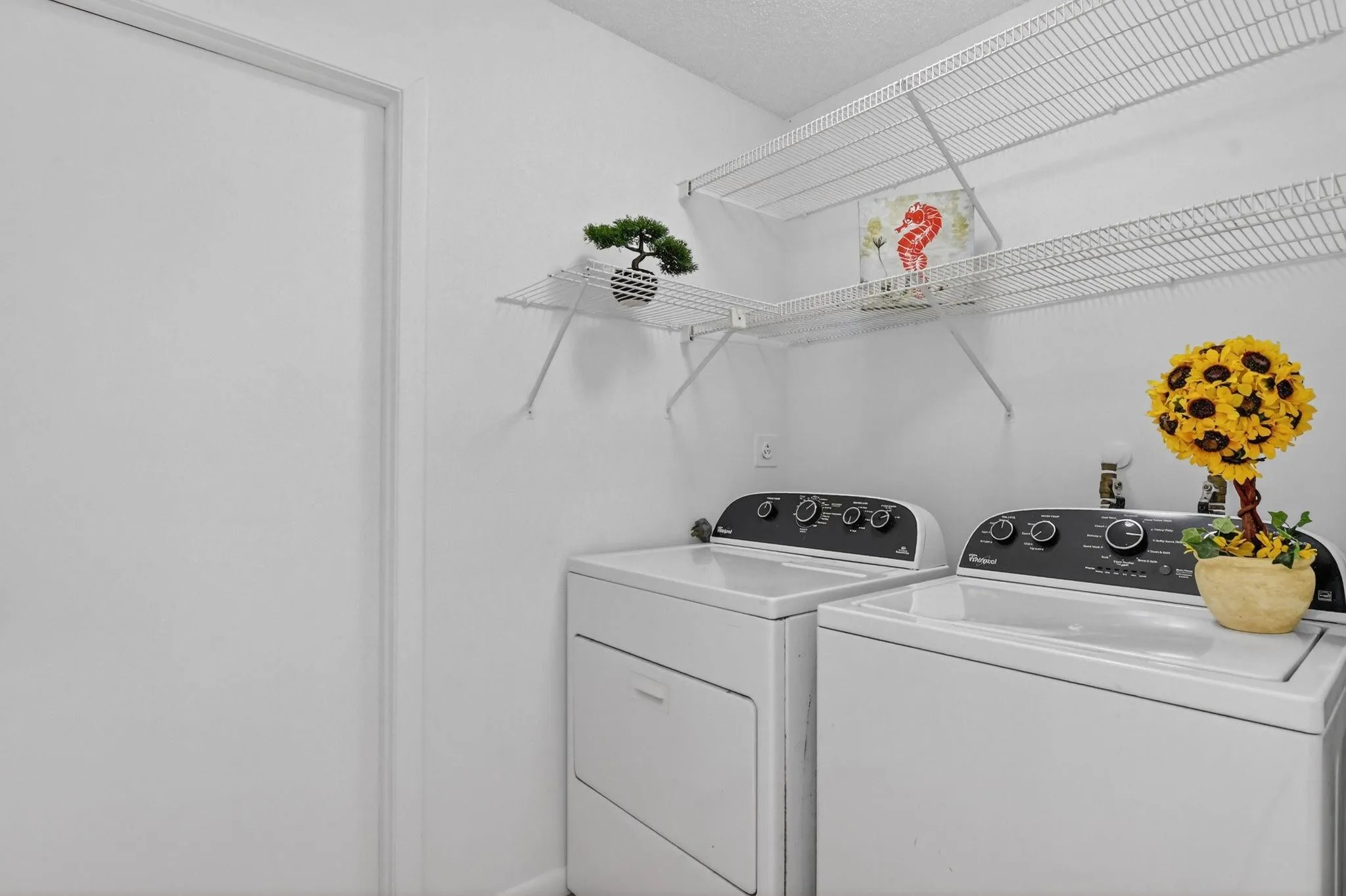 Laundry room with full sized Whirlpool washer and dryer and extra shelving.