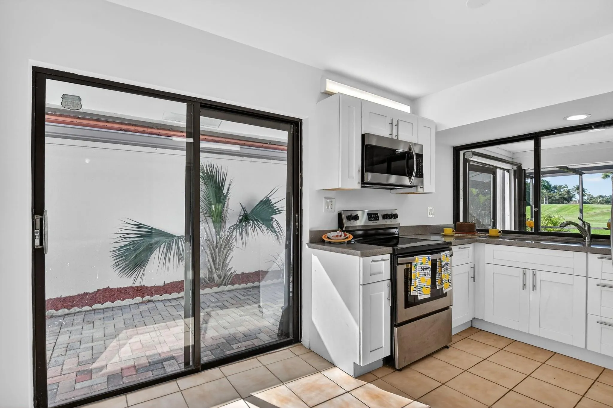 Kitchen features Shaker cabinets. Slider opens to paver patio.