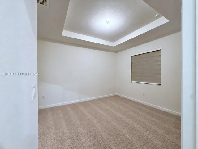 Primary bedroom featuring neutral tones and recessed ceiling detail, offering a comfortable retreat with a clean, modern feel.