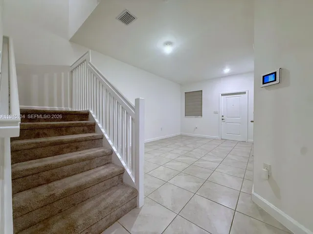 Bright and welcoming entry and main living area featuring tile flooring and an open layout that creates a clean, modern feel.