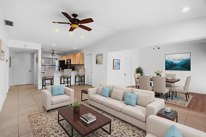 Spacious and light-filled living and dining area featuring neutral tile flooring, recessed lighting, and a ceiling fan, with seamless flow into the adjoining family room—perfect for everyday living and entertaining.