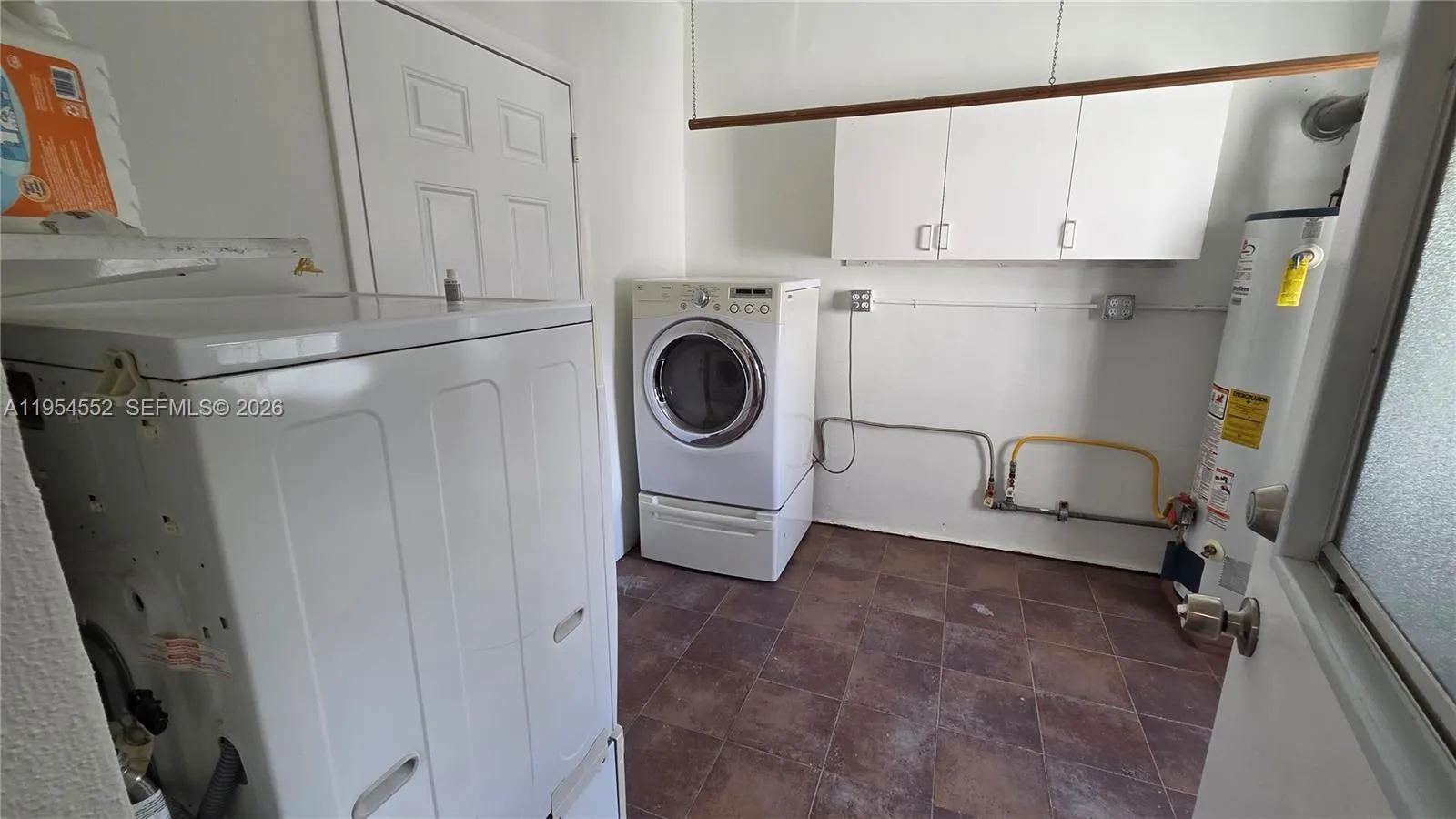 Utility Room with gas dryer and hot water, washer, and utility sink.