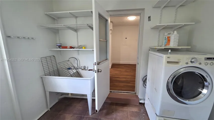Utility Room with gas dryer and hot water, washer, and utility sink.
