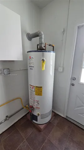 Utility Room with gas dryer and hot water, washer, and utility sink.