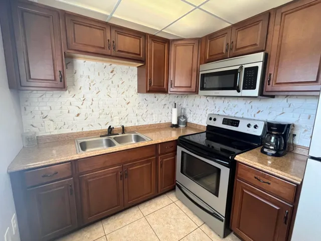 beautifully appointed wood cabinetry along with stainless sink, stainless steel appliances. Formica countertops that look like granite and subway tiled backsplash with design.