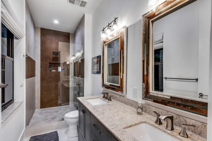 Designer bathroom with custom mirrors, stone counters, and walk-in shower.