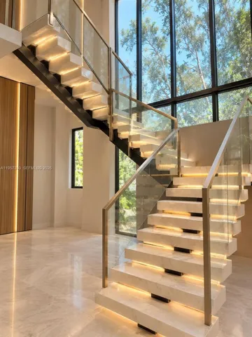Floating staircase featuring stone treads Renderings with integrated under-stair lighting, glass panel railings, metal handrails, and floor-to-ceiling windows
