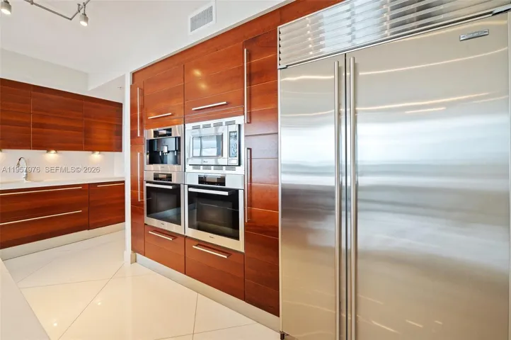 High-end stainless steel appliances including built-in ovens and full-size refrigerator.