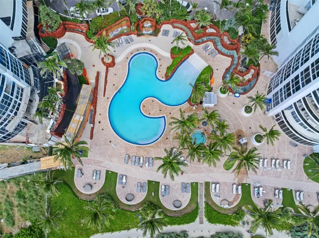 Beautifully landscaped pool deck with lounge areas and palm trees.