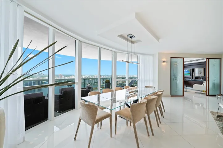 Bright open living and dining area with floor-to-ceiling glass.