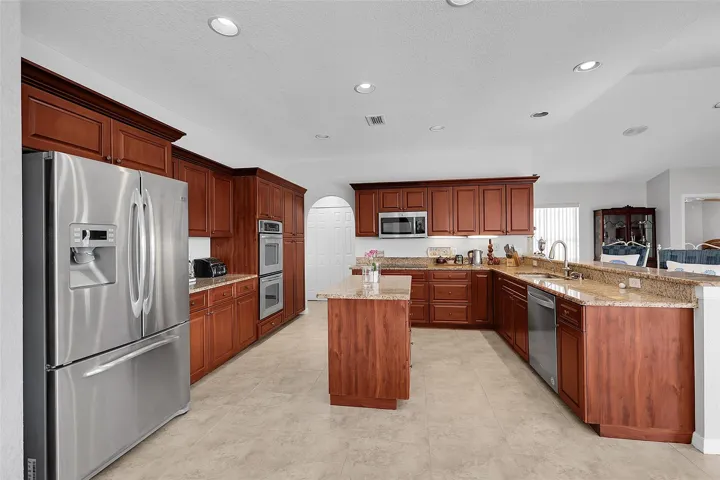 Kitchen featuring stainless steel appliances, an island with drawers, granite countertops, pullout drawers in cabinets, turntables in corner cabinet and recessed lighting