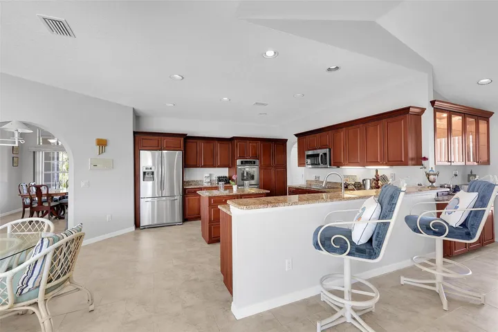 Kitchen featuring a breakfast bar, arched walkways, stainless steel appliances, a peninsula, and light stone counters