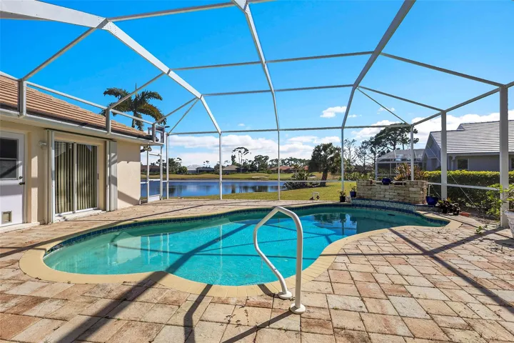 Outdoor pool with a waterfall, pavered patio, water and golf course view. You have a front row seat to the putting adventures!