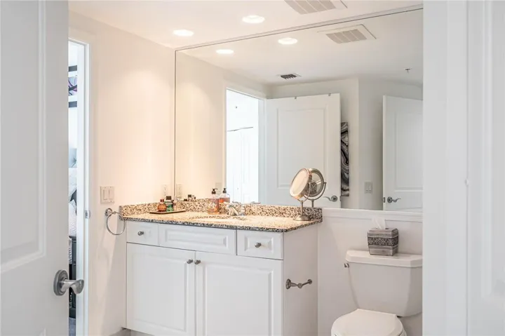 Vanity with granite countertops, plenty of storage and a separate linen closet