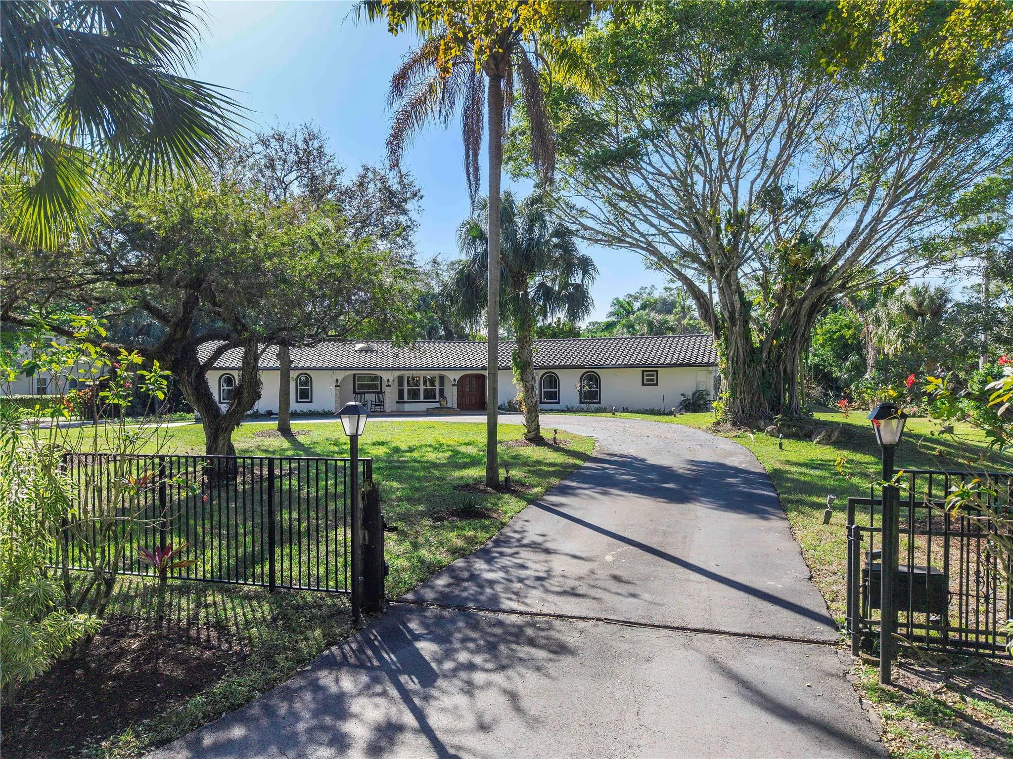 The front of the home with lots of open garden for children to play, Electric gate & fully fenced surrounded gardens with a circular driveway for at least 16 cars