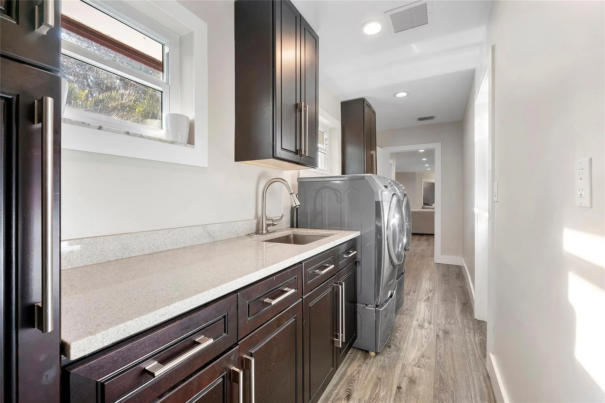 The laundry room in the big house has lots of folding & storage space and its own sink, matching cabinets to the kitchen in walnut with chrome hardware,