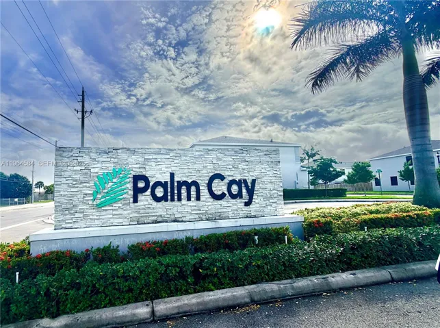Stone-veneer community monument sign featuring dimensional lettering and integrated tropical landscaping