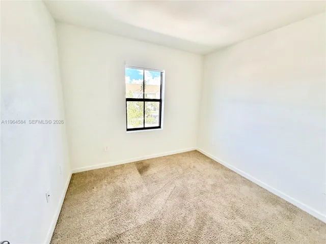 Interior room featuring neutral wall-to-wall carpeting and a window with a black-finish frame