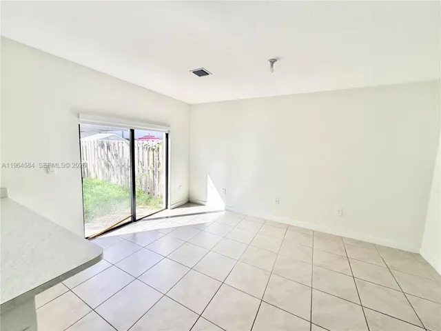 Neutral-toned tile flooring, sliding glass door, and exterior wooden fencing