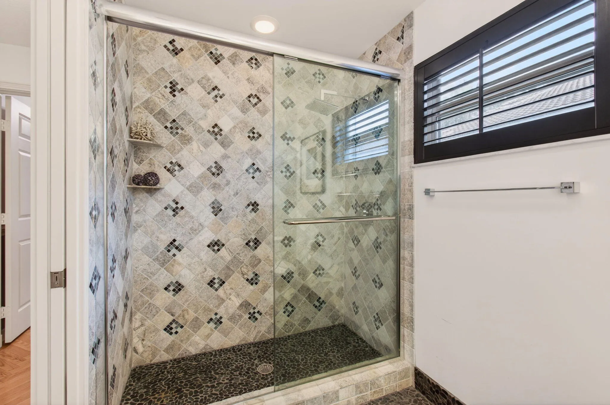 Plantation shutter for privacy and black pebblestone floor, which continues into shower