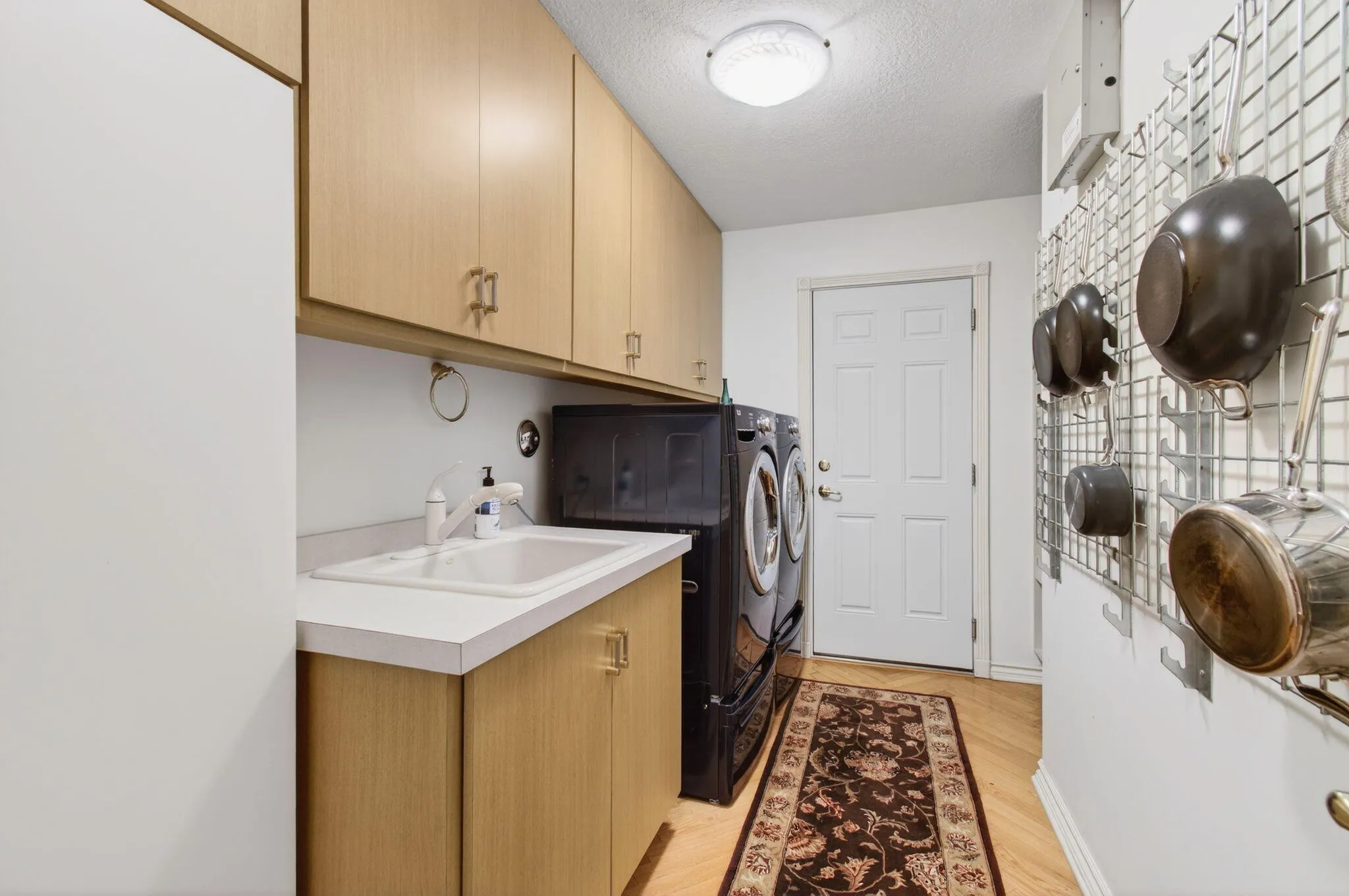 A large sink, ample cabinetry for large pots and pans, and additional storage for laundry items