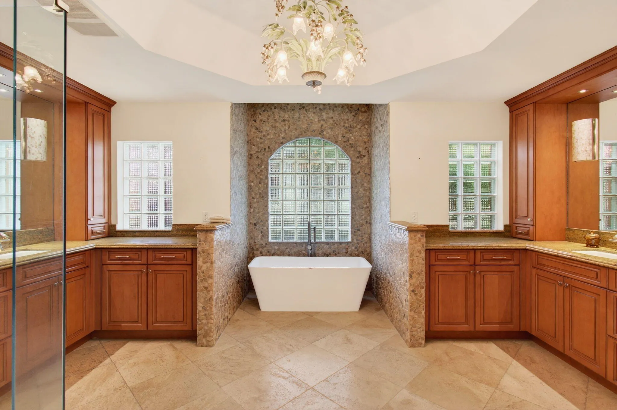 Freestanding soaking tub is the centerpiece of the room, set beneath a large glass block window for light and privacy