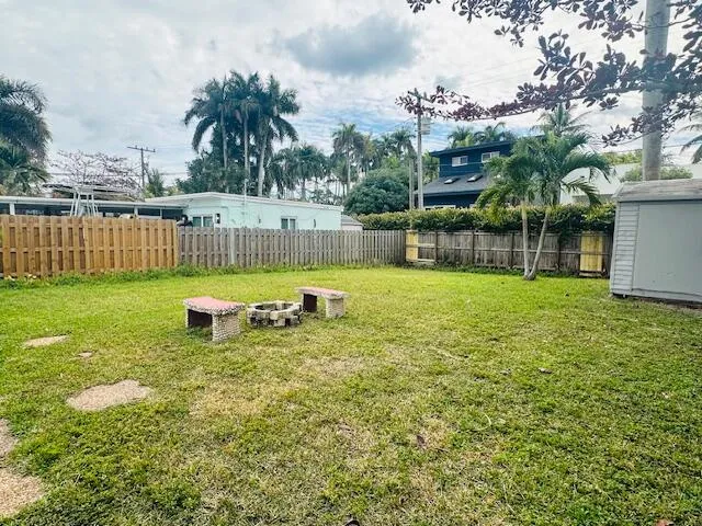 Large fenced in yard with fire pit and utility shed