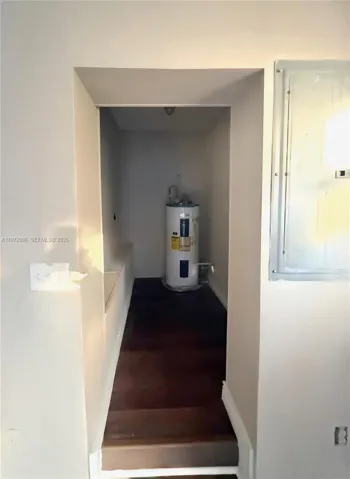 Utility alcove featuring a dedicated water heater unit and a recessed electrical service panel