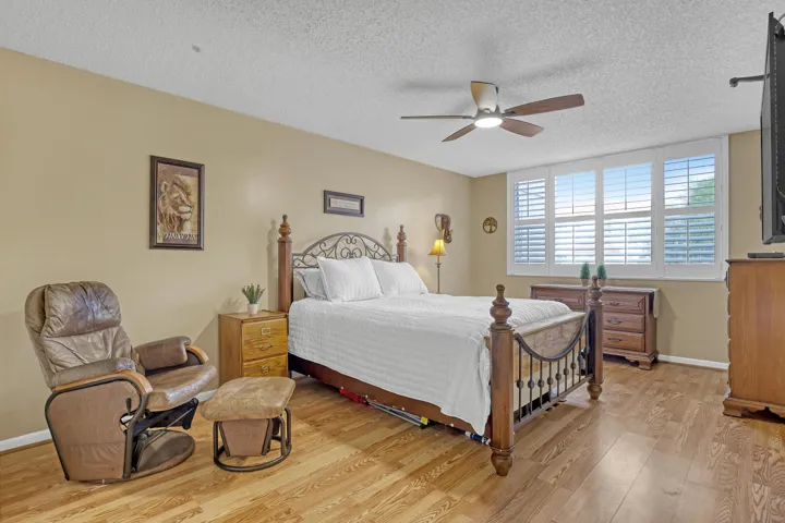 A generously sized primary bedroom with warm flooring and abundant natural light creates a relaxing retreat.