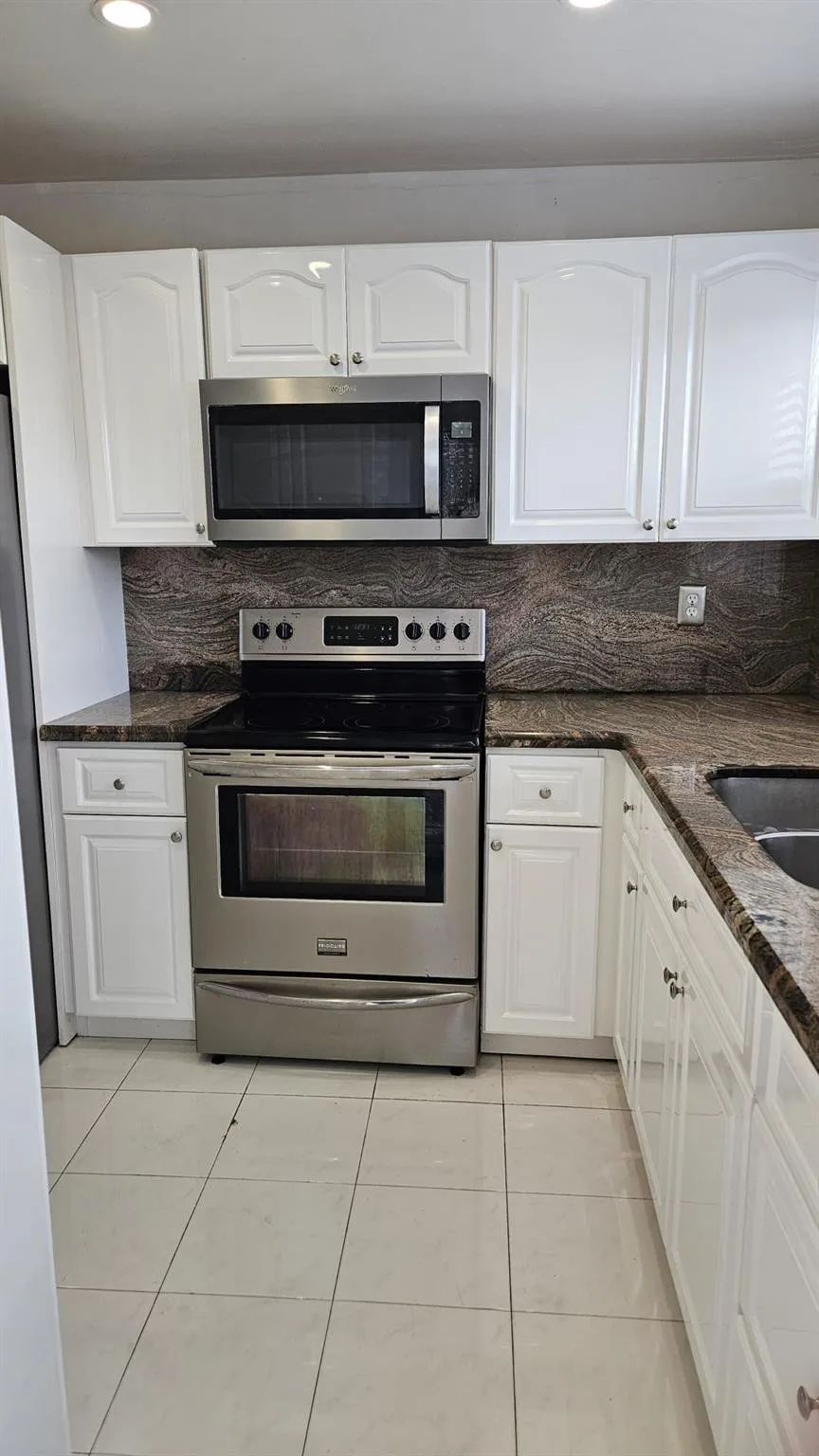 Beautiful kitchen from different angle; stainless steel stove and built-in microwave