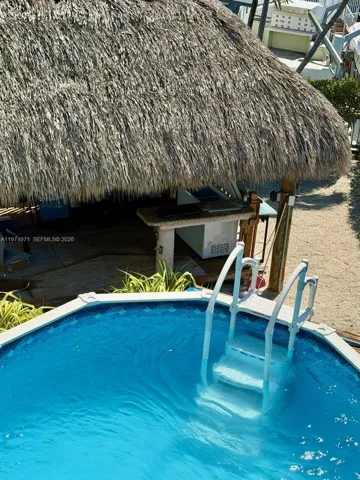Avobe ground pool with tiki and deck