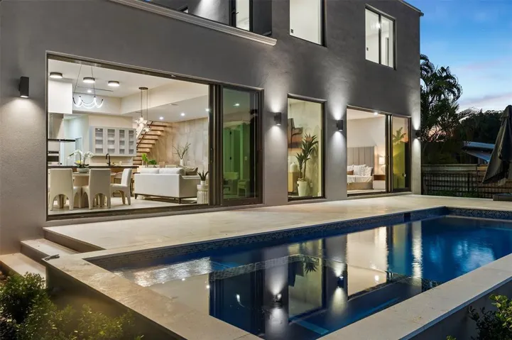 Swimming pool with tiled interior, expansive paved patio, and contemporary exterior wall lighting