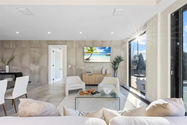 Expansive living space featuring floor-to-ceiling windows, recessed lighting, and large format wall panels