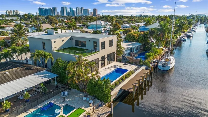 Contemporary structure with flat roofline, private balcony, ground-level pool, and water frontage with dock