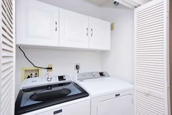 Maytag washer/dryer in laundry room inside condo plus extra cabinetry.