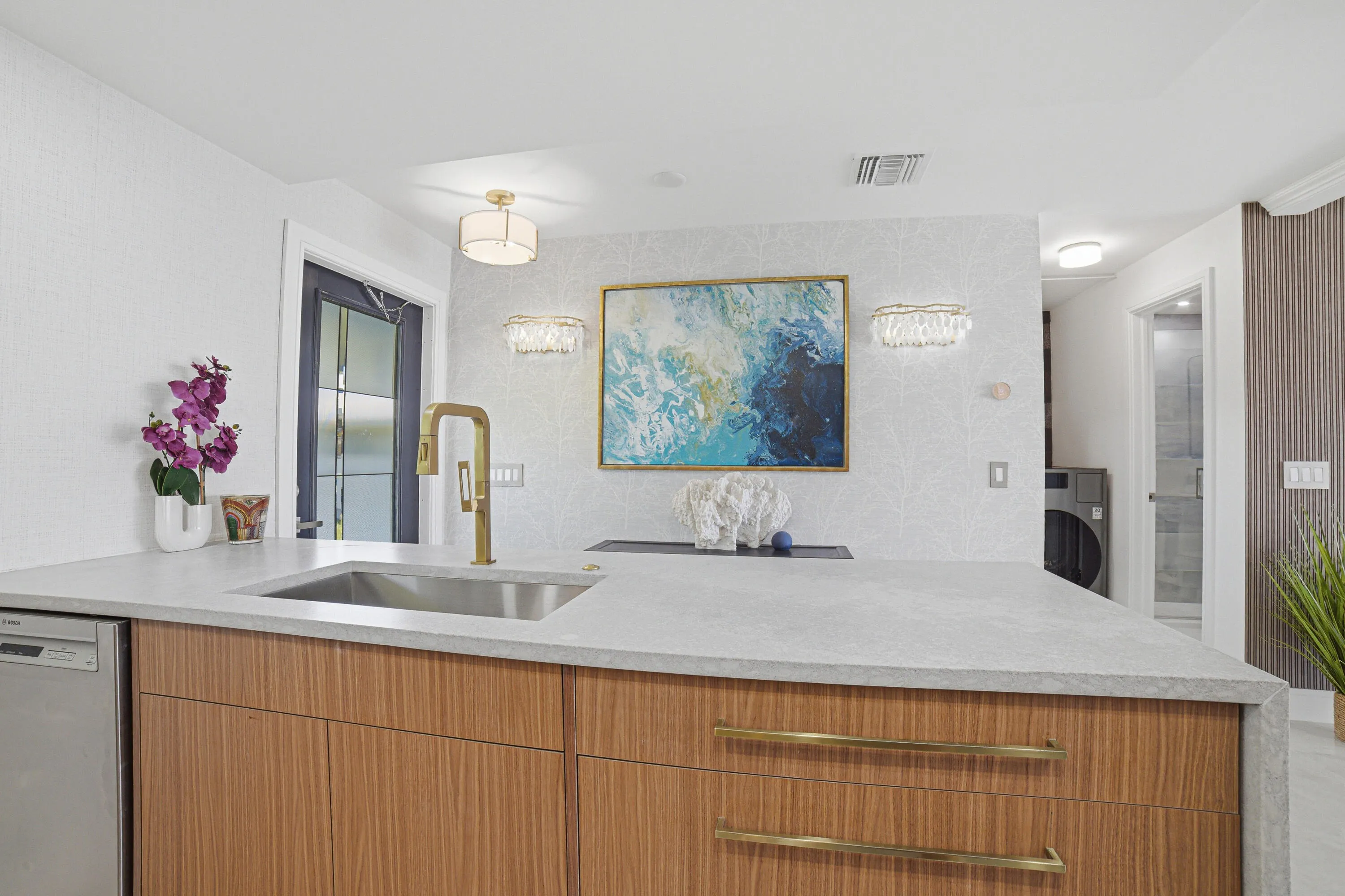 Detail of large drawers to the right of the deep sink, the stainless steel dishwasher is conveniently located to the left of the sink.