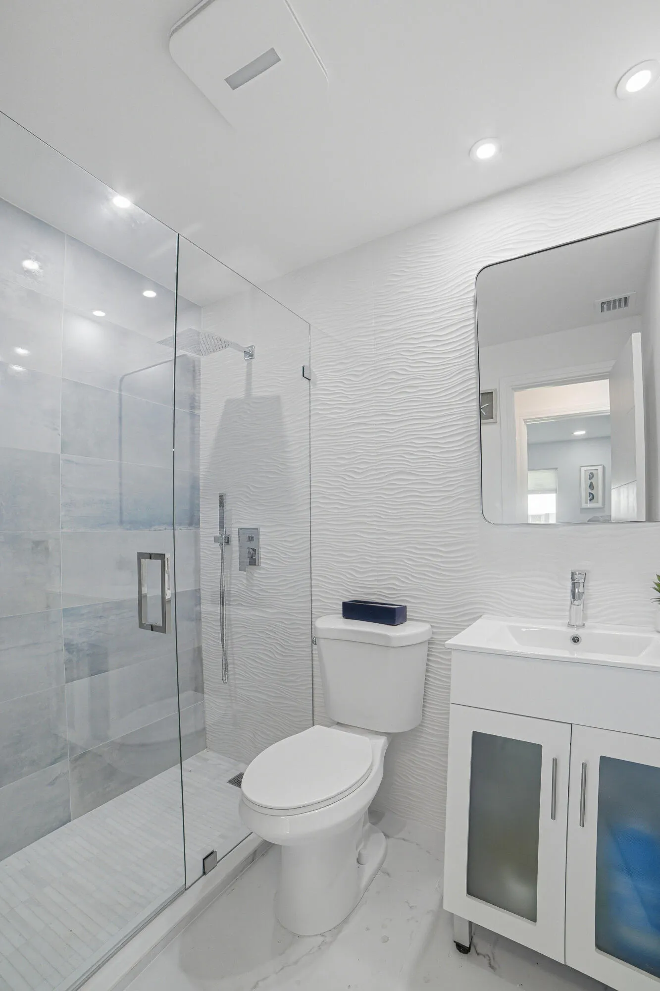 The second bathroom features a refined design, highlighted by a blue accent on the vanity cabinet.