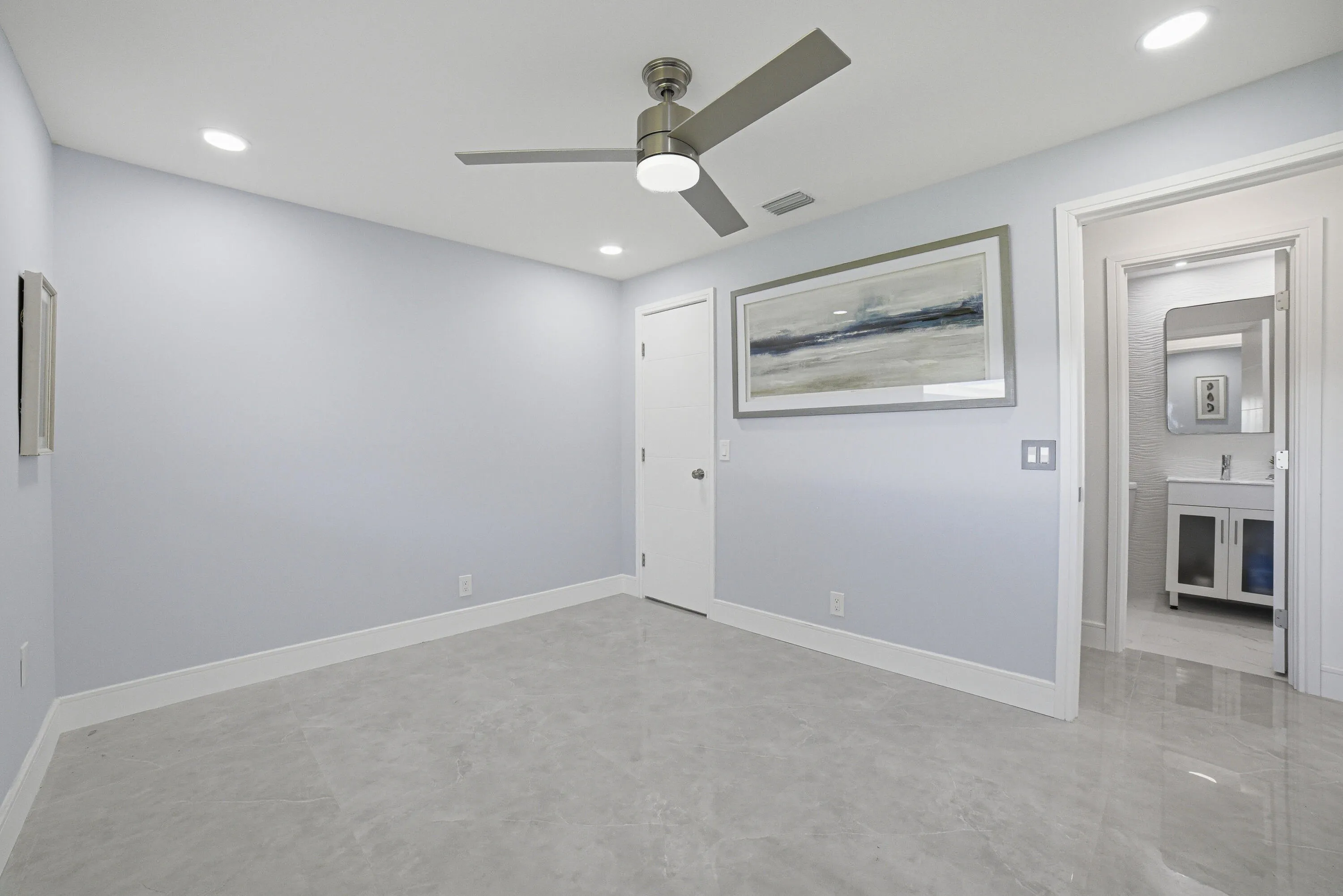 The second or guest bedroom is roomy, showcasing large floor tiles and soft light gray walls.