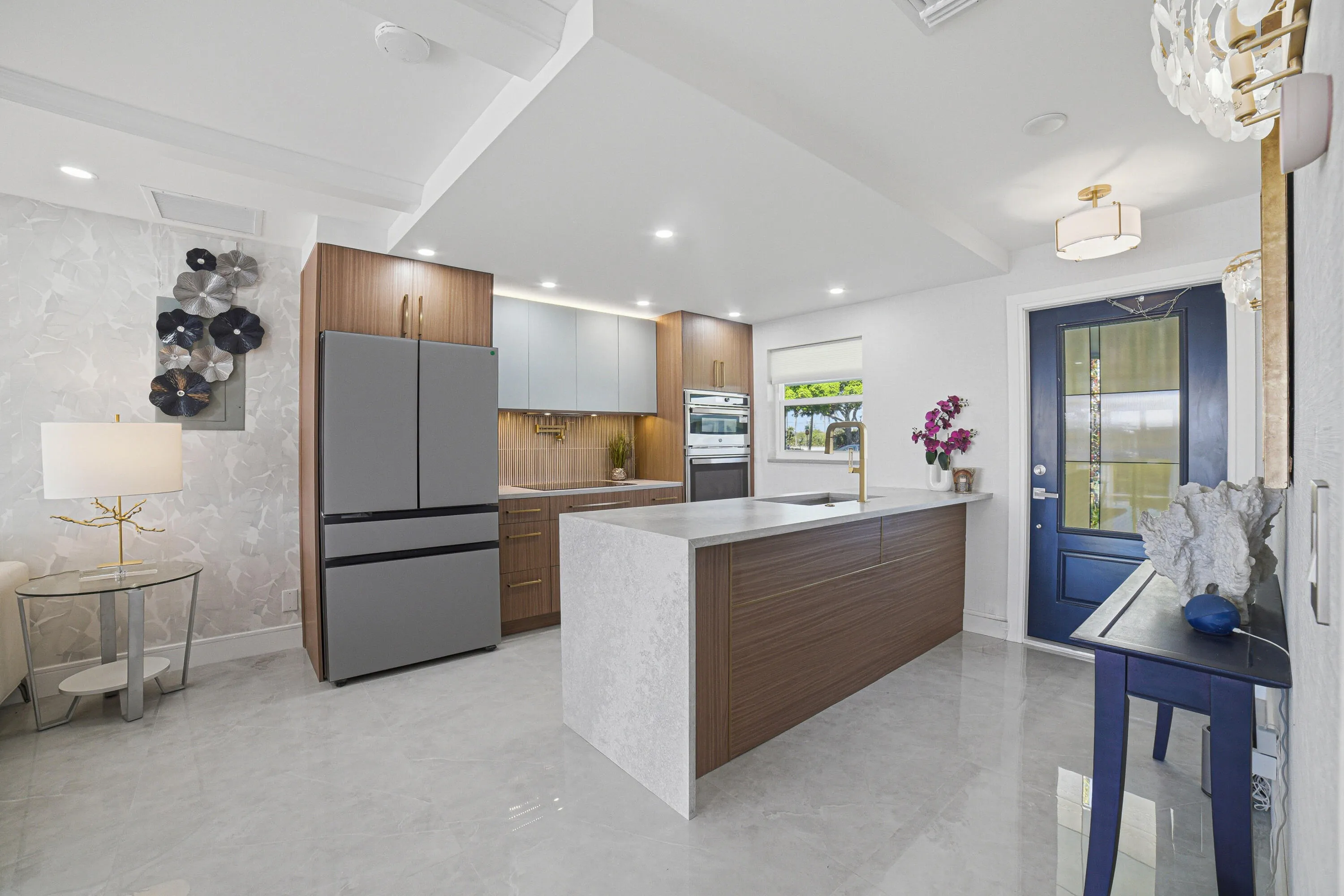 Take note of the spacious four-door stainless steel refrigerator featuring French doors. The large quartz countertop includes a waterfall edge, while the deep stainless steel farmhouse sink, dishwasher, and extra-large drawers offer both style and functionality.