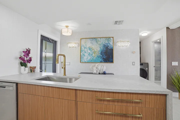 Detail of large drawers to the right of the deep sink, the stainless steel dishwasher is conveniently located to the left of the sink.