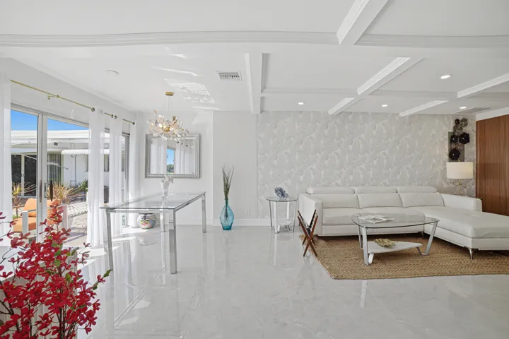 Living room accommodates a big couch, coffee table, a large TV seats on a suspended media console.