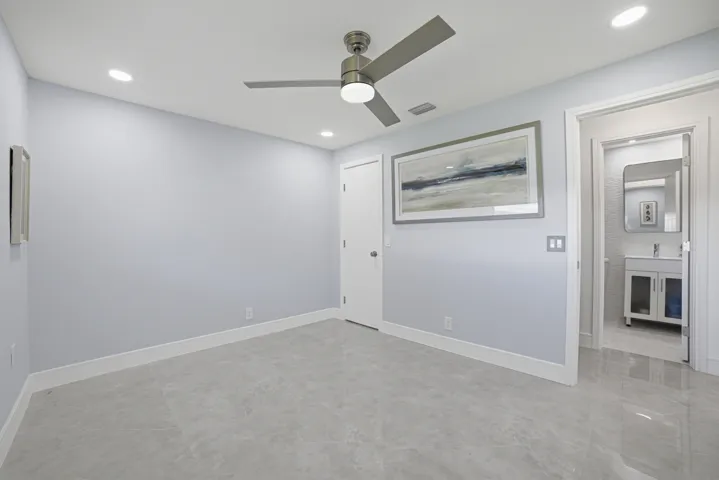 The second or guest bedroom is roomy, showcasing large floor tiles and soft light gray walls.