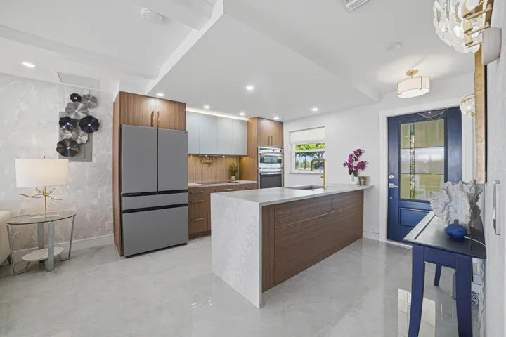 Take note of the spacious four-door stainless steel refrigerator featuring French doors. The large quartz countertop includes a waterfall edge, while the deep stainless steel farmhouse sink, dishwasher, and extra-large drawers offer both style and functionality.