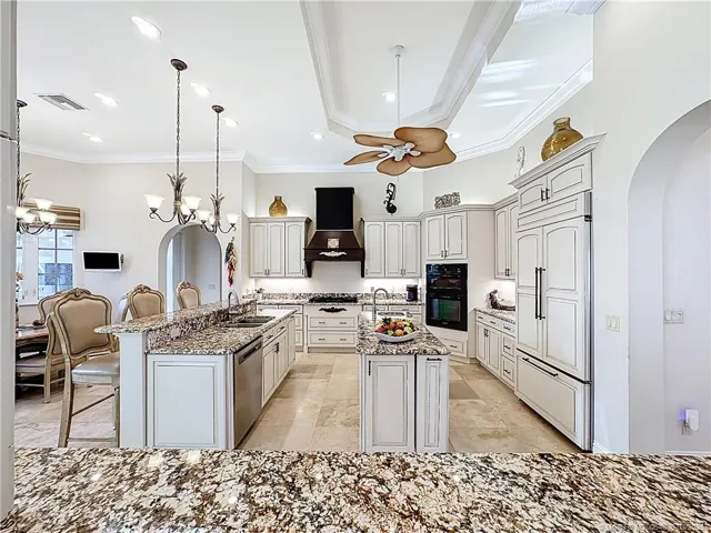 High ceilings, tray ceilings with crown molding, gas stove, to the right on the island on the left in front of the 2nd Island is a extra ice maker and sprice pull out. double siinks, convection microwave, with oven in the wall. Breakfast area to sit and relax and watch TV included on the wall. Look out to the pool area and bar with a summer Kitchen.